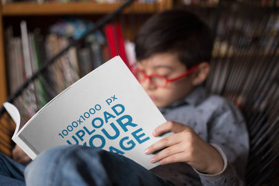 Mockup of a Square Book Cover Read by a Boy Sitting on an Acapulco Chair