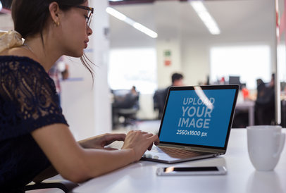 Mockup of a Woman Working on her MacBook at a Modern Office
